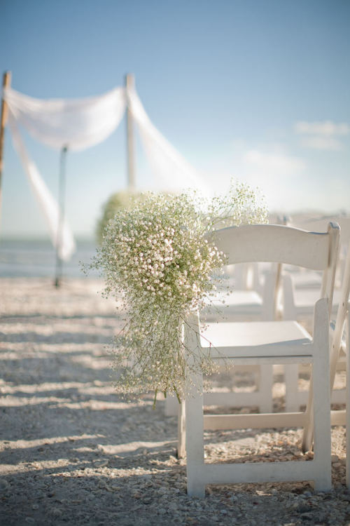 Baby's breath accents aisle seating in this romantic Florida beach wedding